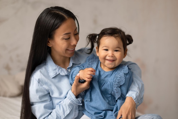 Alegre mamãe japonesa e adorável filha bebê posando em casa