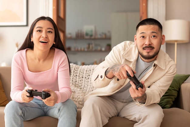 Foto alegre marido japonês e esposa jogando videogame em casa