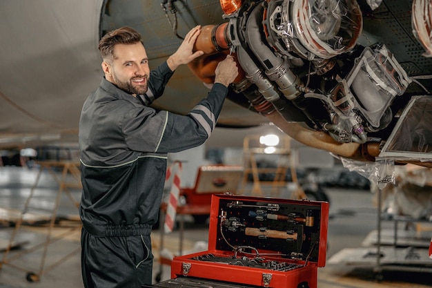 Alegre mecânico masculino reparando aeronaves no hangar