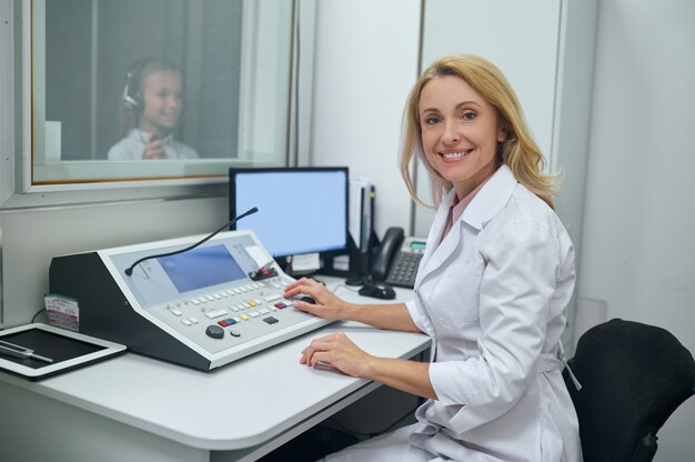 Foto alegre médico de mediana edad realizando una prueba de audiometría