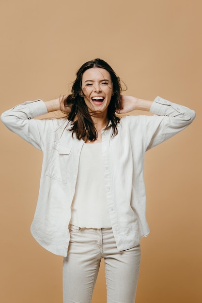 Alegre menina bonita feliz olhando para a câmera sorrindo rindo sobre fundo bege