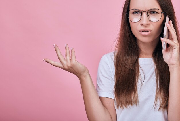 Foto alegre menina encantadora em uma camiseta branca falando no celular