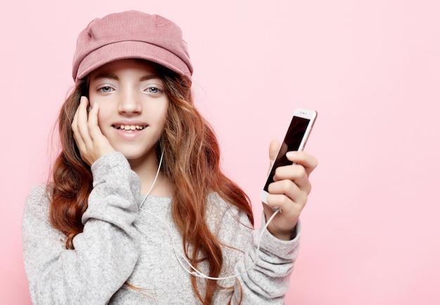 Alegre menina incrível vestindo rosa ouvindo música com fones de ouvido isolados no fundo rosa