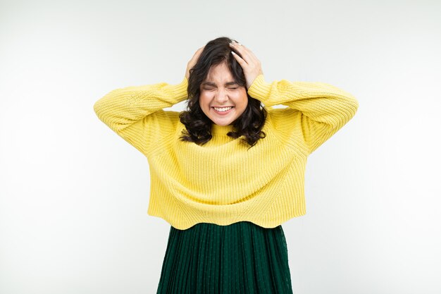 Alegre menina morena feliz em uma camisola amarela e saia verde sobre fundo branco