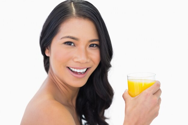 Alegre modelo sensual nua com copo de suco de laranja