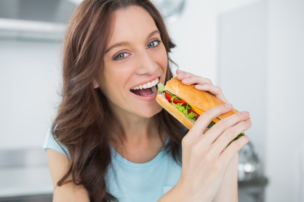 Alegre morena comiendo sándwich