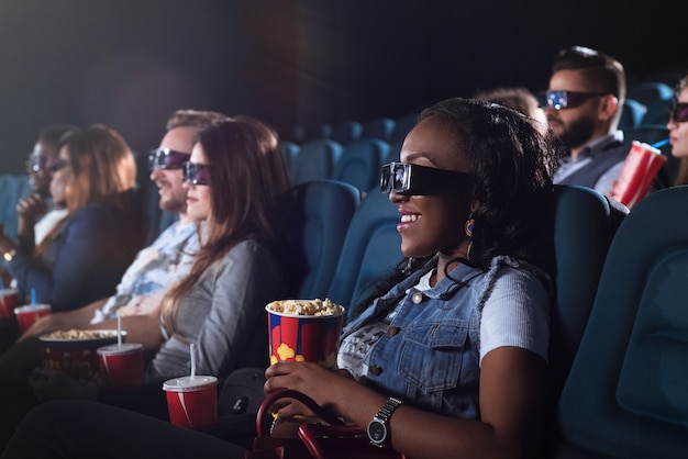 alegre mujer africana con gafas 3D mientras ve una película en el cine