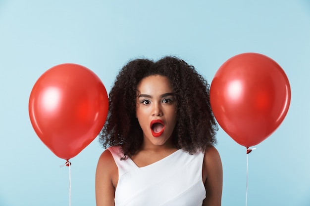 Alegre mujer africana con vestido celebrando con globos aislados