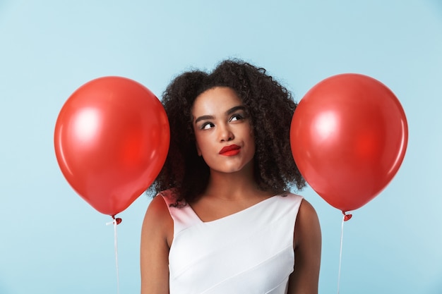 Alegre mujer africana con vestido celebrando con globos aislados