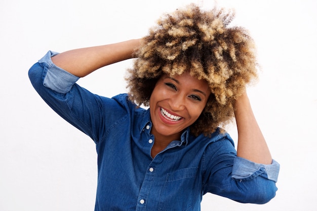 Alegre mujer afroamericana riendo con las manos en el pelo