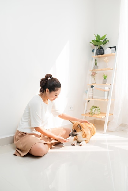 Alegre mujer asiática jugando con su perro Corgi