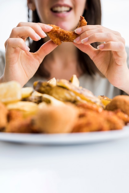 Alegre mujer comiendo pollo asado