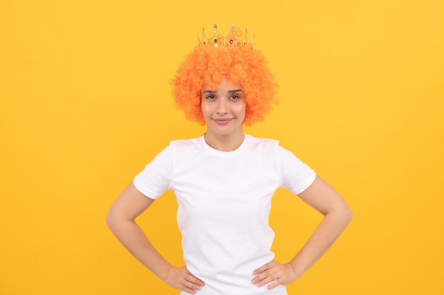 Alegre mujer egoísta extraña con peluca de payaso rizado y corona de reina para la alegría de la fiesta