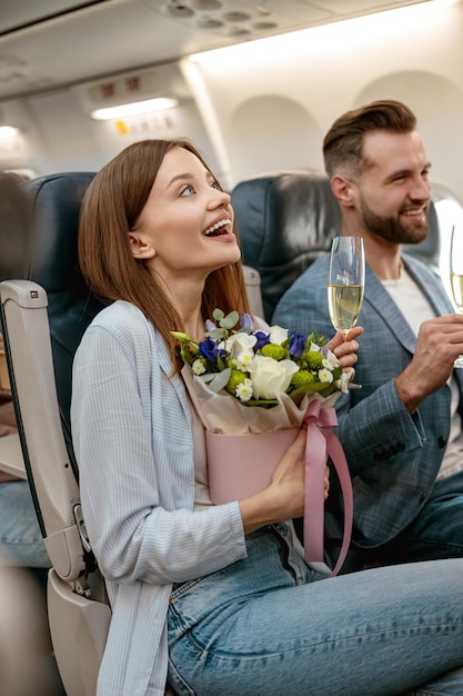 Alegre mujer y hombre bebiendo champán en avión