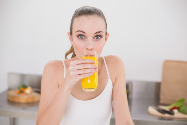 Alegre mujer joven vaso de jugo de naranja