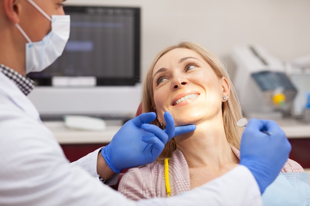 Alegre mujer madura sonriendo a su dentista durante el examen médico