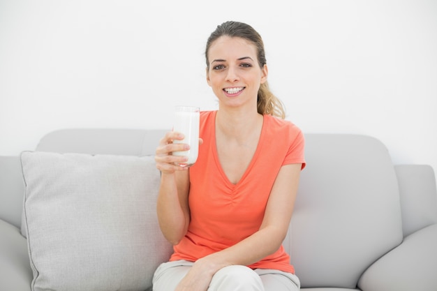 Alegre mujer morena sosteniendo un vaso de leche sonriendo felizmente a la cámara