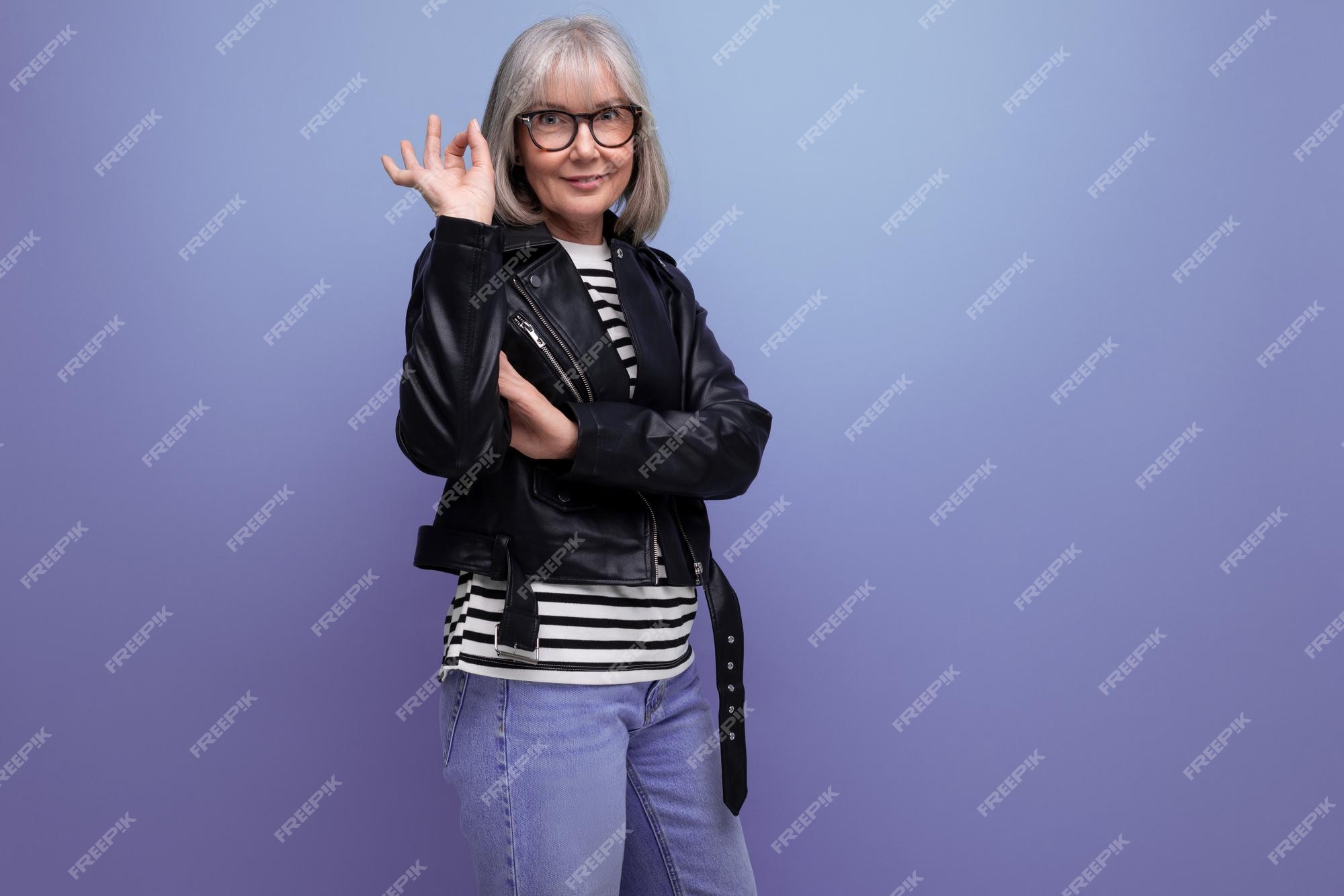 Alegre mujer de negocios de mediana edad con cabello gris en una chaqueta rockera juvenil en un brillante Foto Premium