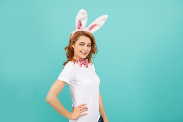 Alegre mujer de Pascua con orejas de conejo sobre fondo azul.