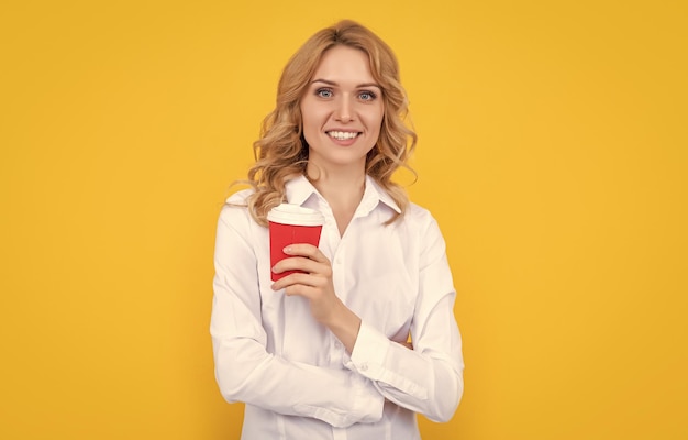 Alegre mujer rubia con taza de café por la mañana sobre fondo amarillo