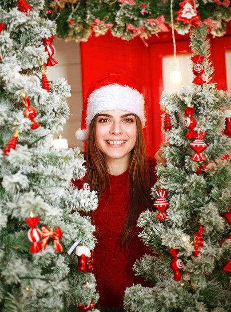 Alegre mujer soñadora de Santa en escena Árbol de Navidad con decoración