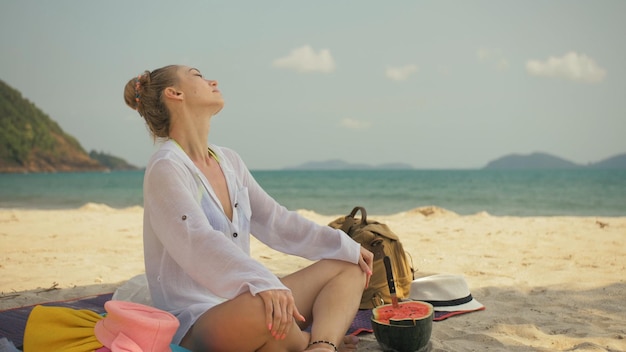 La alegre mujer sosteniendo y comiendo rebanadas de sandía en la arena tropical playa mar retrato attra