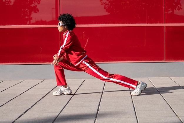 Alegre mulher afro-americana fazendo esportes em um fundo vermelho em um dia ensolarado