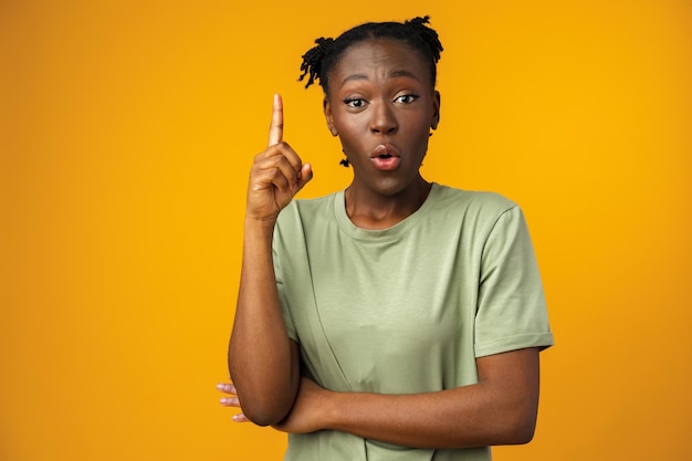 Alegre mulher afro aponta para copiar espaço no estúdio amarelo