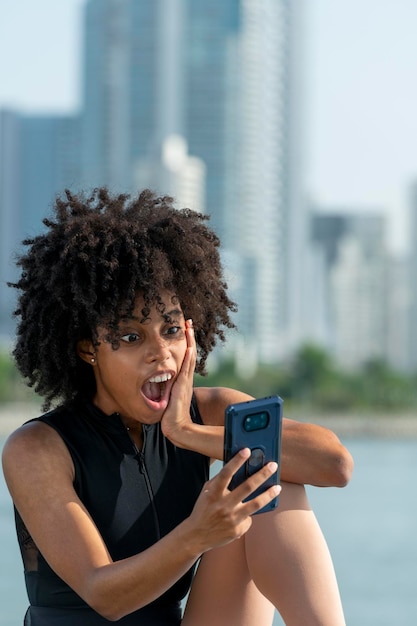 Alegre mulher afro latina com gesto surpresa durante a videochamada através do smartphone foto de stock