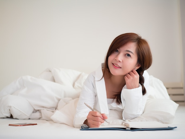 Alegre mulher asiática bonita sorri e feliz na cama no quarto