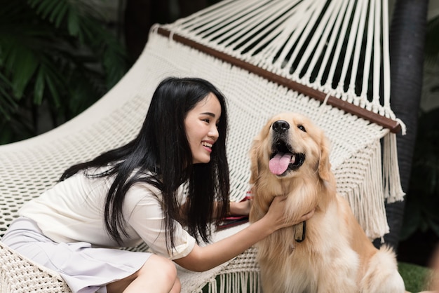 Alegre mulher asiática brincando com seu cachorro golden retriever no jardim em casa