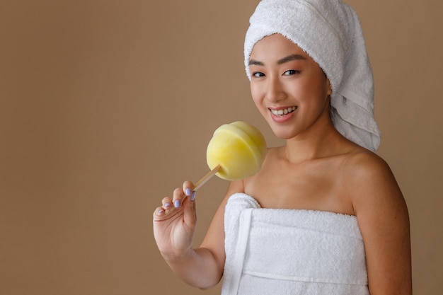 Alegre mulher asiática segurando esponja de banho de pirulito