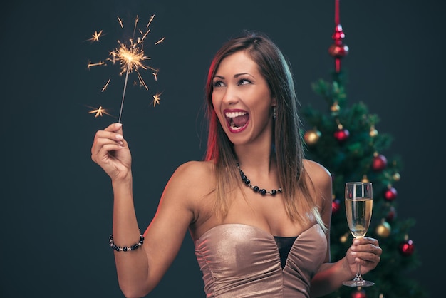 Alegre mulher bonita comemorando o ano novo. Ela está se divertindo com diamante e champanhe.