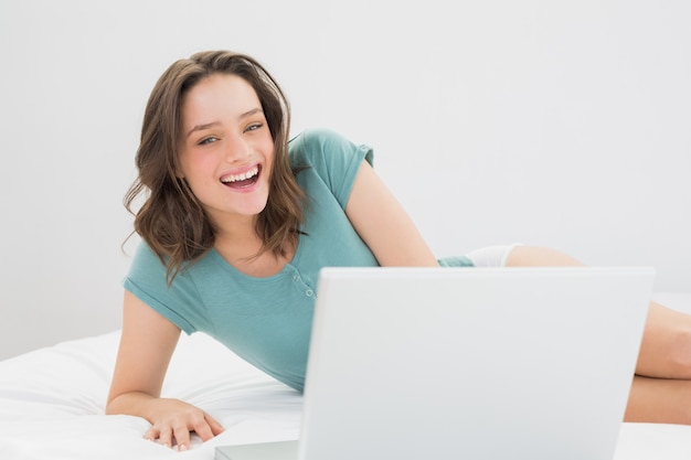 Foto alegre mulher casual com laptop na cama