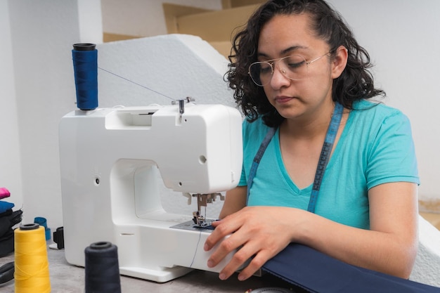 Alegre mulher costurando enquanto está sentado em seu local de trabalho na oficina de moda