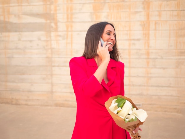 Alegre mulher de vestido vermelho falando no smartphone