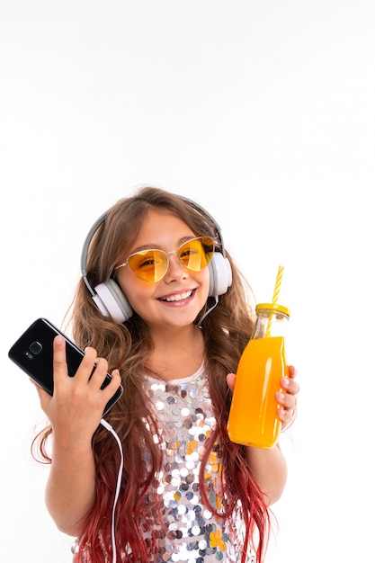 Alegre mulher em fones de ouvido, ouvindo música em copos laranja