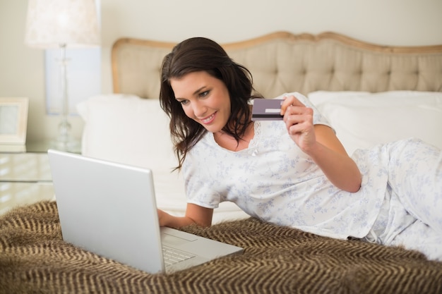 Alegre mulher marrom bonita comprando online com seu laptop