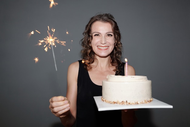 Alegre mulher segurando o bolo de aniversário