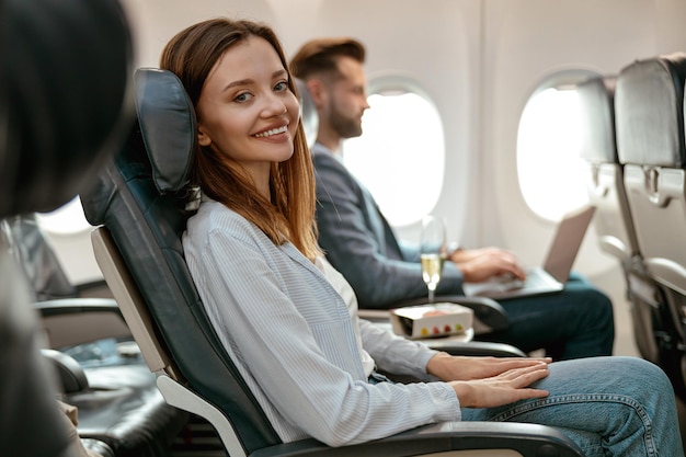 Alegre mulher sentada na cadeira do passageiro no avião