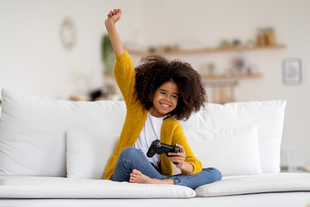 Alegre niña afroamericana jugando videojuegos