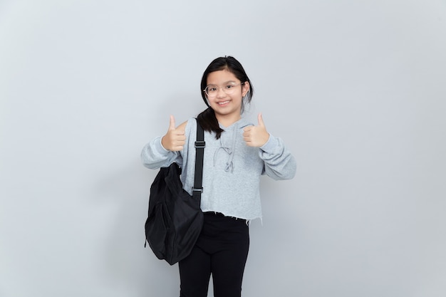 Una alegre niña asiática sonriente lleva una mochila escolar