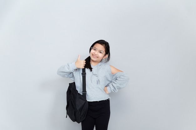 Una alegre niña asiática sonriente lleva una mochila escolar