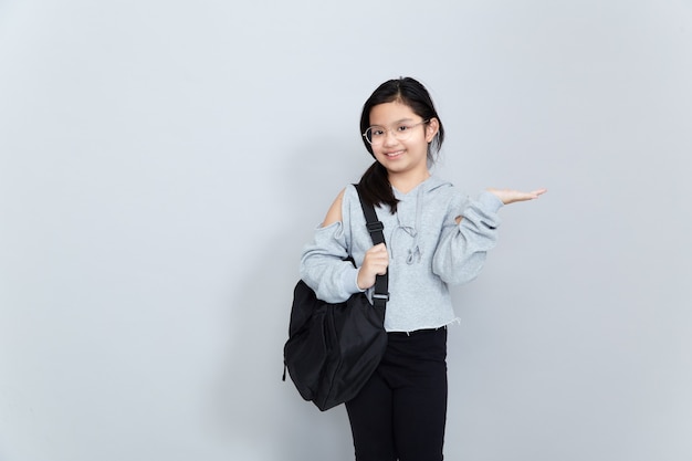 Una alegre niña asiática sonriente lleva una mochila escolar