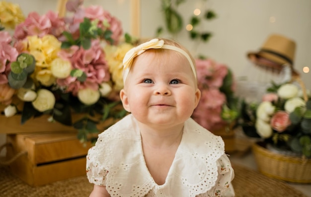 Foto una alegre niña caucásica con un traje de color con una diadema se arrastra sobre la alfombra entre cajas de flores