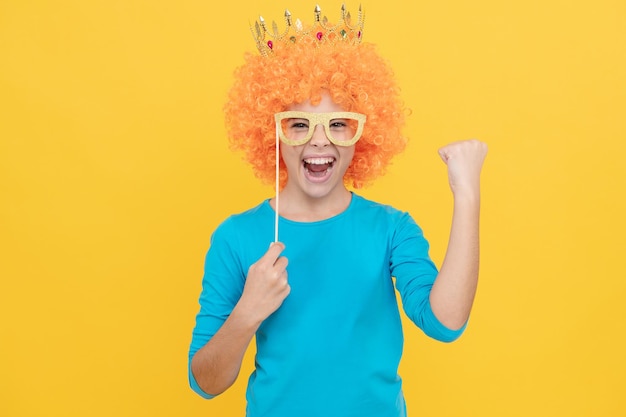 Alegre niña egoísta con peluca rizada y diadema de princesa usa gafas de fiesta éxito