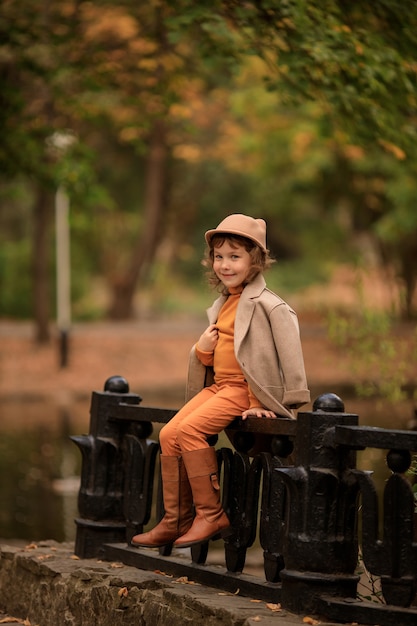 Alegre niña feliz con un sombrero en un paseo en el otoño por el lago en el parque