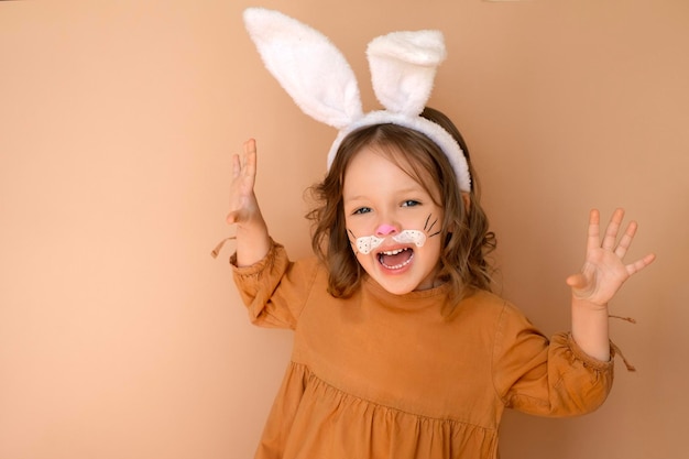 Una alegre niña riendo con orejas de conejo y cara pintada.