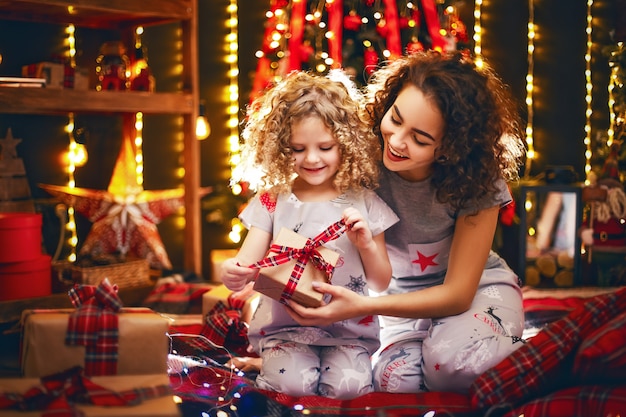 Alegre niña rizada linda y su hermana mayor intercambiando regalos.