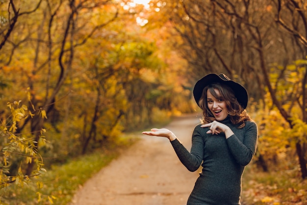 Foto alegre niña con sombrero negro posa en el parque